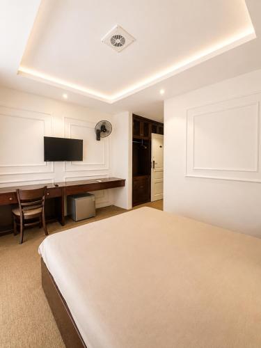 a bedroom with a bed and a desk with a television at X-Stay Cloud in Hai Phong