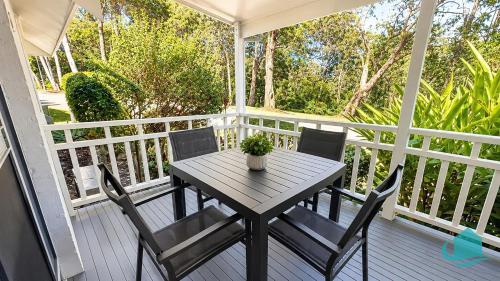 a wooden table and chairs on a porch at Plover Executive Deluxe Villa 25 in Cams Wharf