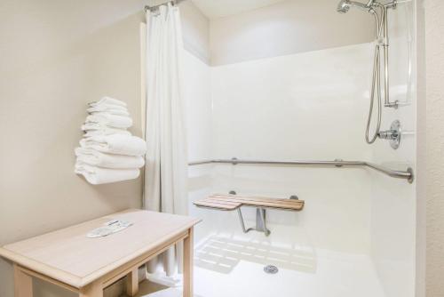 a bathroom with a shower and a table and towels at Microtel Inn & Suites Claremore Route 66 in Claremore