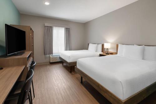 a hotel room with two beds and a flat screen tv at ECHO Suites Extended Stay by Wyndham Houston Katy West in Katy