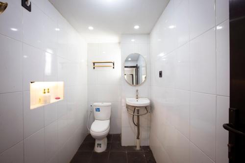 a white bathroom with a toilet and a sink at Lovia Villa Dieng in Kejajar