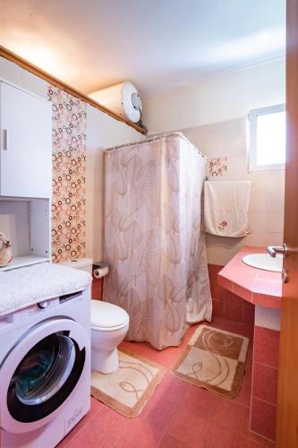a bathroom with a washing machine and a toilet at Miraluna View in Mesochórion