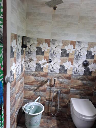 a bathroom with a toilet and flowers on the wall at Eleeza Homestay in Cochin