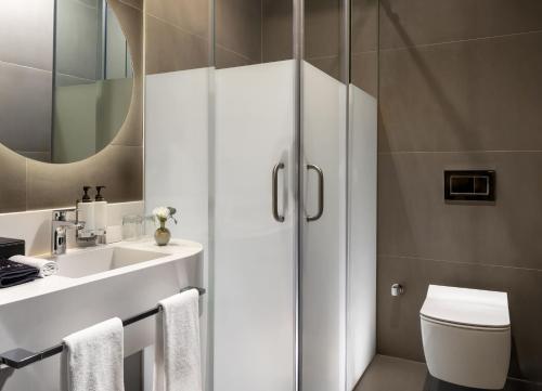 a bathroom with a sink and a toilet and a mirror at Bomonti Suites Istanbul in Istanbul