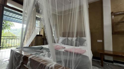a bedroom with a canopy bed with pink pillows at Forest Rawana homestay Ella in Ella
