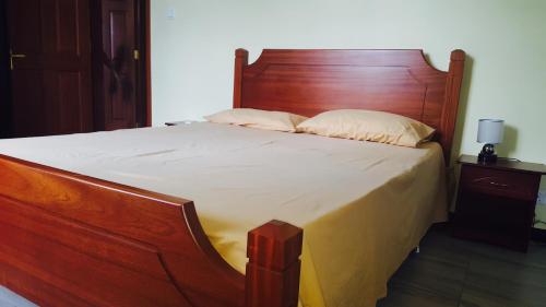 a large bed with a wooden headboard and two pillows at Lotus Villa in Flic-en-Flac