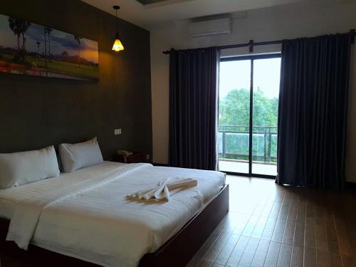 a bedroom with a large bed with a large window at KN Guesthosue in Phumĭ Réach Born (1)