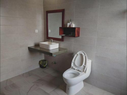 a bathroom with a toilet with a mirror and a sink at KN Guesthosue in Phumĭ Réach Born (1)