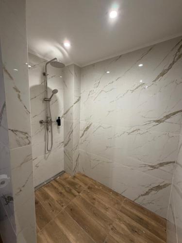 a bathroom with a shower with white marble walls at Карпати Кайзервальд апарт in Karpaty
