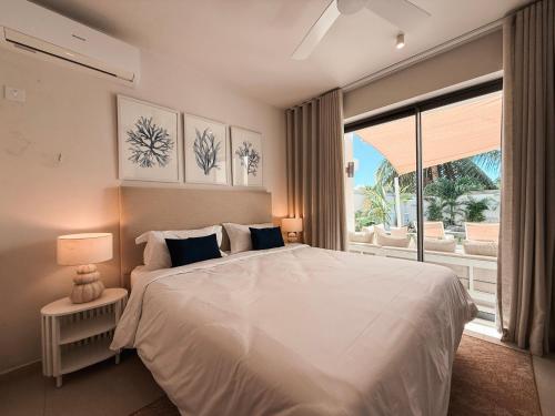 a bedroom with a white bed and a large window at North Island View Family Duplex with private pool by LOV Mauritius in Grande Gaube