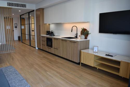 a kitchen with wooden cabinets and a flat screen tv at Kove Apartment - G05 in Kiama