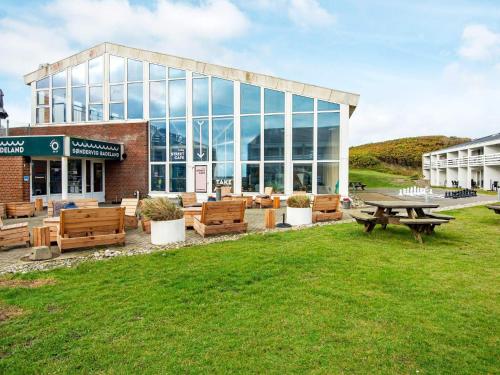 a building with a picnic table and benches in the grass at Søndervig Holiday Center in Ringkøbing