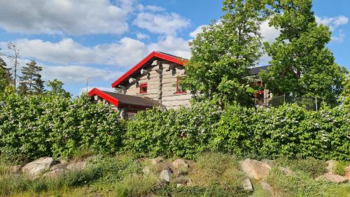 a house with a red roof on a hill with bushes at Glampingtält in Österbybruk