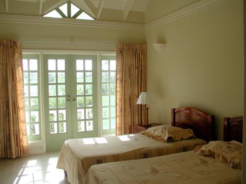 a bedroom with two beds and a large window at Villa Sans-Souci in Lowlands