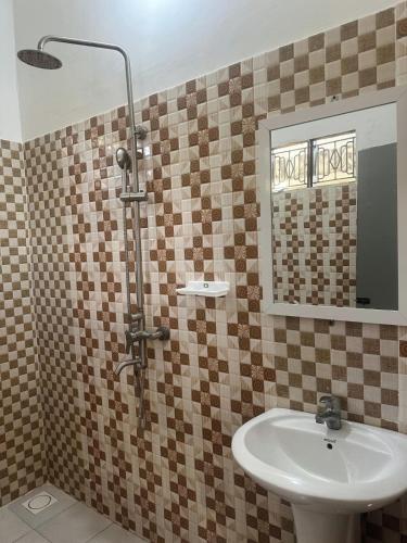 a bathroom with a sink and a shower with a mirror at Kipe House Nungwi in Nungwi