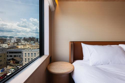 a bedroom with a bed and a window with a city at KIORI Hotel Teramachi in Kyoto