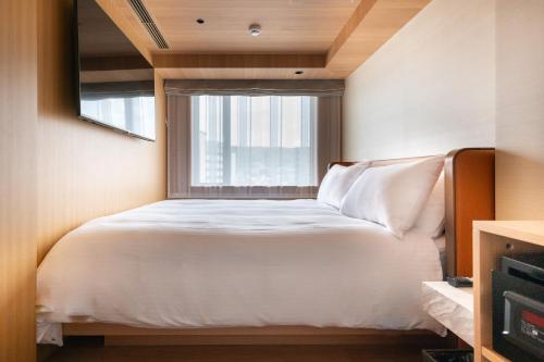 a bedroom with a white bed and a window at KIORI Hotel Teramachi in Kyoto