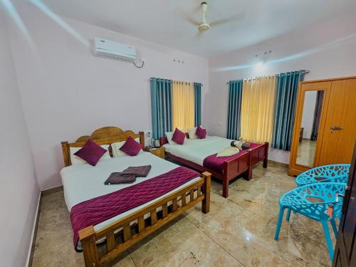 a bedroom with two beds and a chair in it at Varkala Escape Resort in Varkala