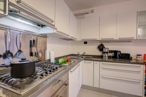 a kitchen with white cabinets and a stove top oven at Lenni Apart. Swimming Pool and lake + WIFI - Happy Rentals in Leggiuno