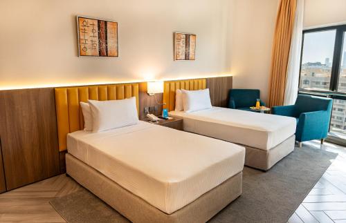 a hotel room with two beds and a chair at Majestic Central Hotel in Dubai
