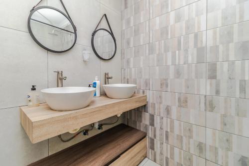 a bathroom with two sinks on a wooden counter with mirrors at Urban Escapes - LINDEN COTTAGE in Johannesburg