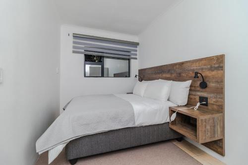a bedroom with a large bed with a wooden headboard at Urban Escapes - LINDEN COTTAGE in Johannesburg