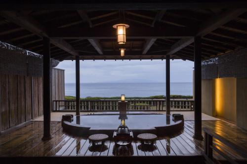 a hot tub on a deck with a view of the ocean at Bousui in Higashiizu