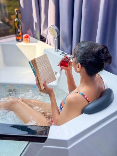 a woman is sitting in a bath tub reading a book at The Blackberry Retreat Kandy in Kandy