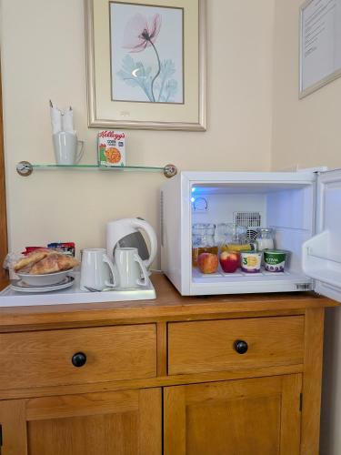 a microwave on top of a wooden cabinet with food at Sunset House in Penrith
