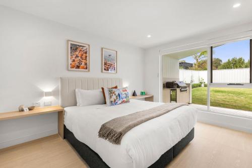 a bedroom with a large bed and a large window at Casa Bianca - Fireplace with Swimming Pool in Callala Beach