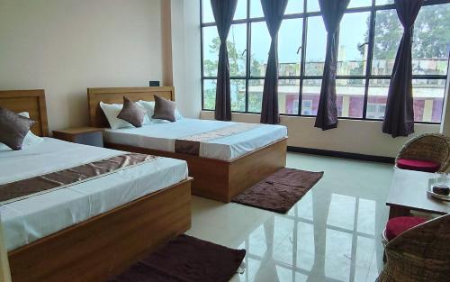 a bedroom with two beds and a large window at Marigold in Kalimpong