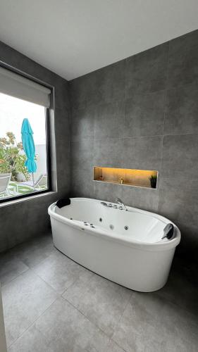 a bath tub in a bathroom with a window and an umbrella at Rove Chalet in á¸¨arÄdÄ«