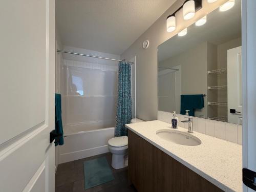 a bathroom with a sink and a toilet and a mirror at Beautiful New House in Alpine Park, Calgary in Calgary