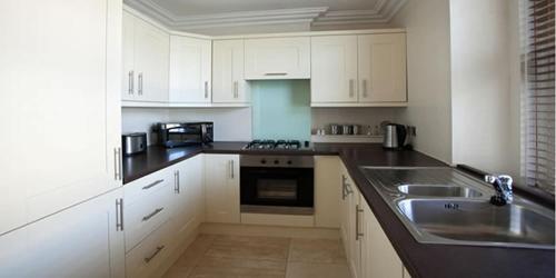 a kitchen with white cabinets and a sink at Victoria Mansions Hotel Apartments in Weston-super-Mare