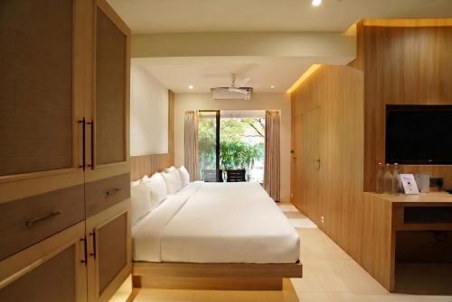 a bedroom with a large white bed and a television at Bougainvillea in Nagaon