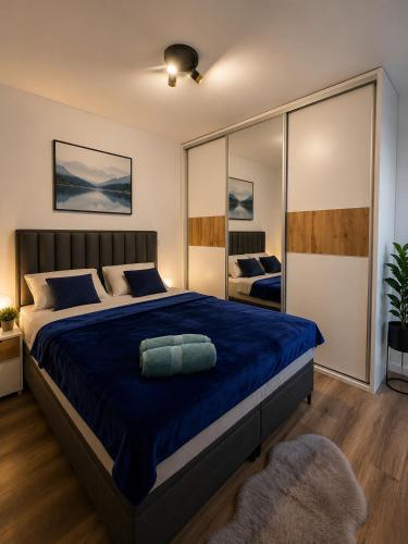 a bedroom with a large bed with a blue blanket at Urban Nest Tuzla in Tuzla