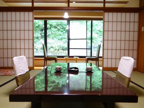 a dining room with a table and chairs and windows at Takaragawa Onsen Ousenkaku in Minakami