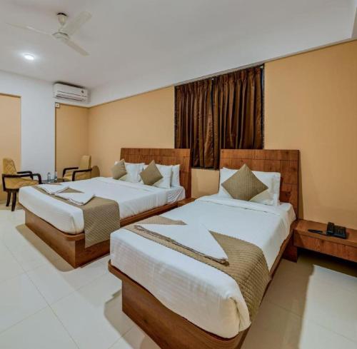a hotel room with two beds and a window at Hotel Grand Heritage Badami in Badami
