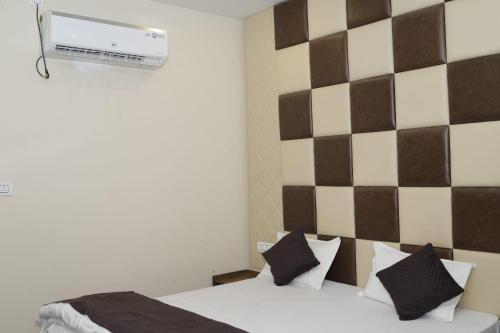 a bedroom with a white bed with black pillows at Doon Sanskaram Hotel in Chūharpur