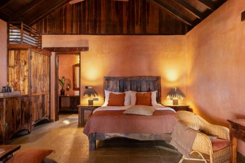 a bedroom with a bed and two tables and a chair at Palm Grove Beach Resort in Mandrem