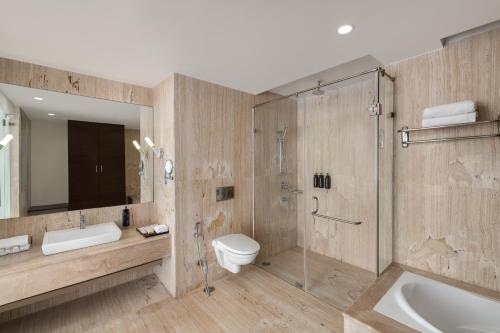 a bathroom with a shower and a toilet and a sink at Ramada by Wyndham Bodh Gaya Mahabodhi in Bodh Gaya