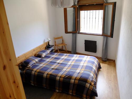 a bedroom with a bed with a plaid blanket and a window at Apartamento Valdenieve VUTE-15-041 in Valdelinares