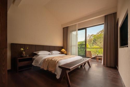 a bedroom with a large bed and a large window at Liaoxin Valley Forest Hotel in Jiezi Ancient Town