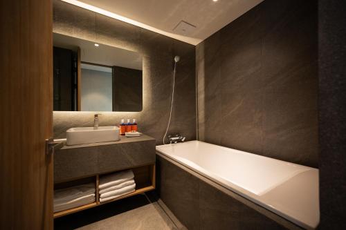 a bathroom with a bath tub and a sink at Hotel Editions Mokpo in Mokpo