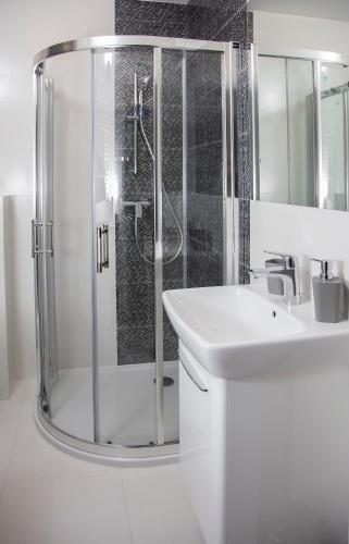 a white bathroom with a shower and a sink at 100-SIO Apartamenty in Koszalin