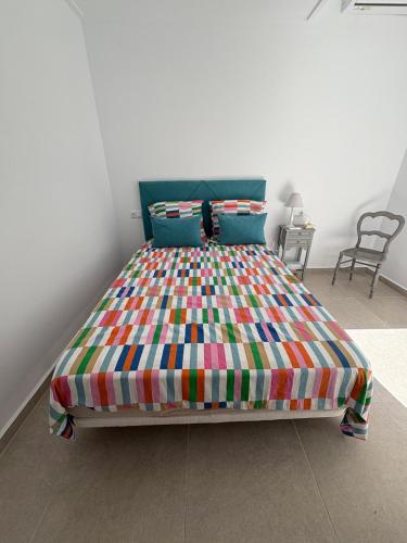 a bed with a colorful comforter in a room at Beau séjour in Pedreguer