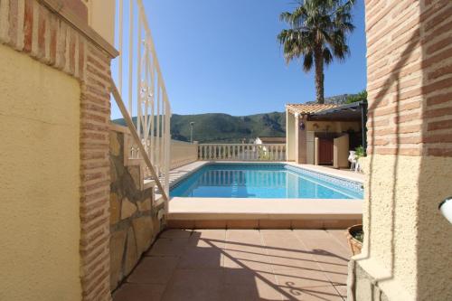 a swimming pool next to a house with a palm tree at Oasis con piscina y jacuzzi para 4 in Adsubia
