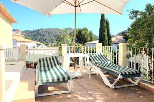 two chairs and an umbrella on a patio at Oasis con piscina y jacuzzi para 4 in Adsubia