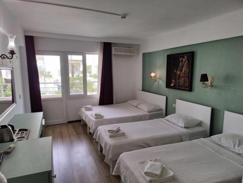 a hotel room with three beds and a window at Datça Stayinn Otel in Datca