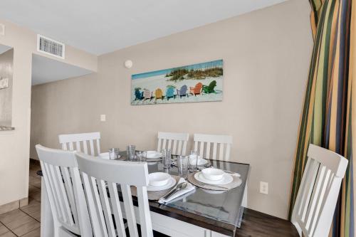 a dining room with a glass table and white chairs at Hosteeva Atlantica Oceanfront Condo in Myrtle Beach